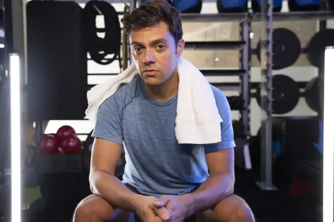 Portrait of young man with towel around his neck in gym.