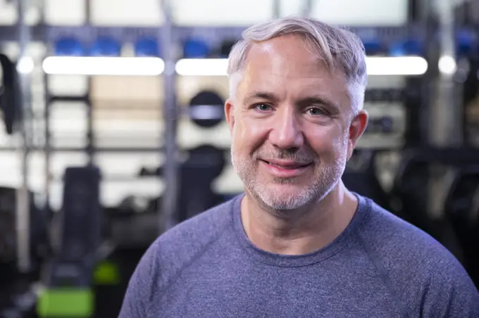 Portrait of fit senior man looking into camera smiling at gym