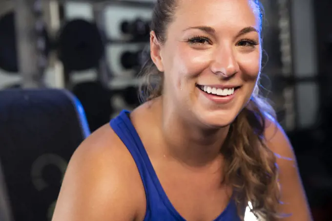 Smiling portrait of a young woman working out in a gym