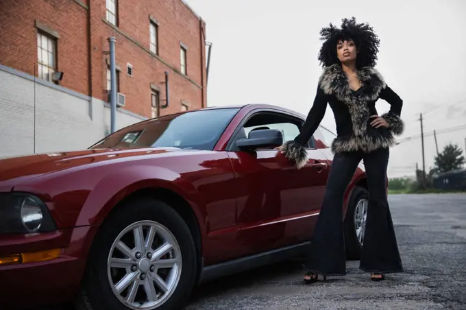 Full length tough portrait of a young African American woman with her car.