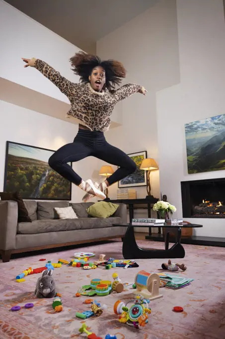 Female ballet dancer and young mother jumping over toys scattered on floor