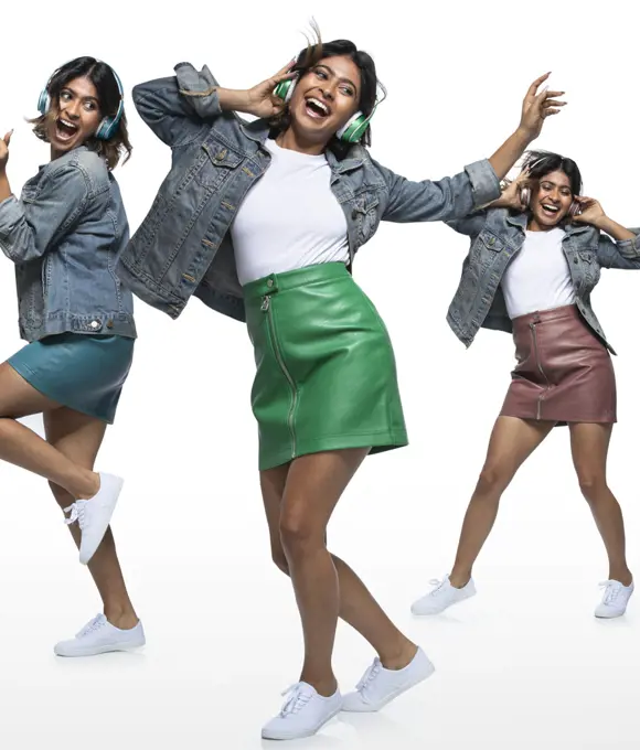 Composite portrait of young woman dancing with headphones wearing leather mini skirt and denim jacket on white background 