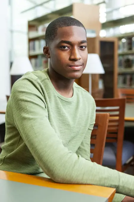 Portrait of confident Black male student in library. 