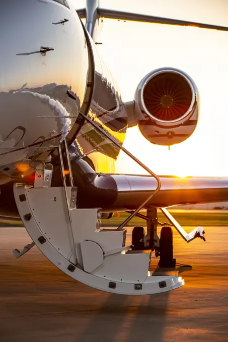 Detail of jet airplane door and stairs  profile open at sunset on tarmac of airport 