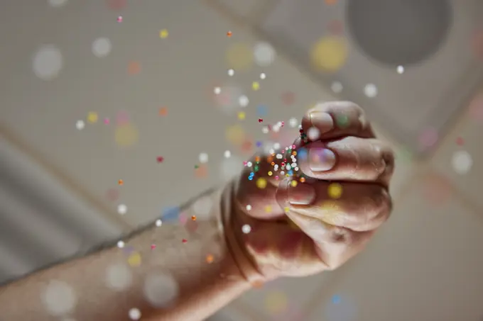 Low angle view of decorative sprinkles falling from bakers fingers onto fresh baked goods 