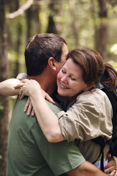 Older couple embracing while hiking on trail through the woods