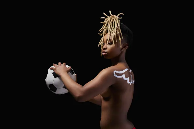 Female athlete with painted wings on her back holding a soccer ball