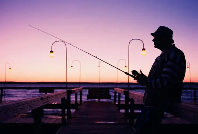 Mature man fishing on a dock in the morning