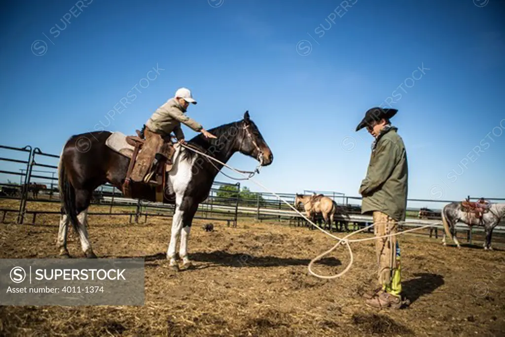 Young cowboy lassoing his father for practice