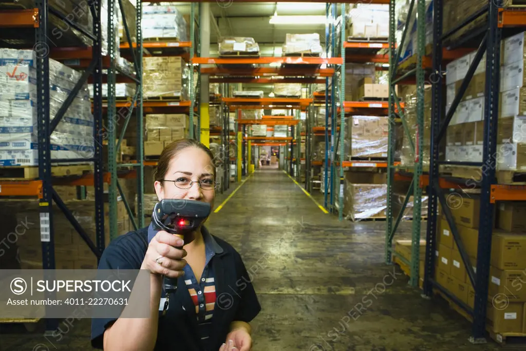 Hispanic woman holding scanner in warehouse