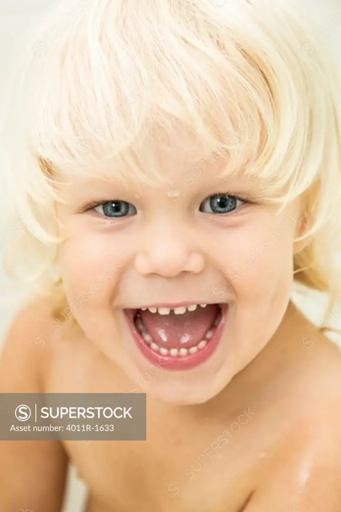 Young blonde boy smiling in bath