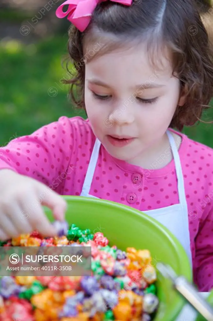Young girl  reaching for colored popcorn