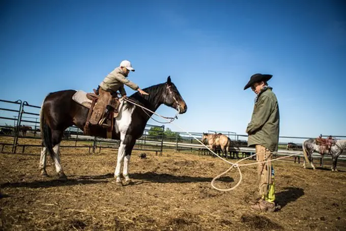 Young cowboy lassoing his father for practice