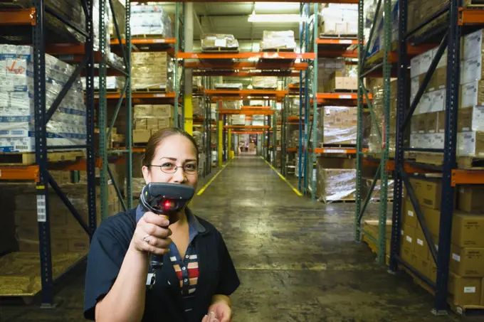 Hispanic woman holding scanner in warehouse