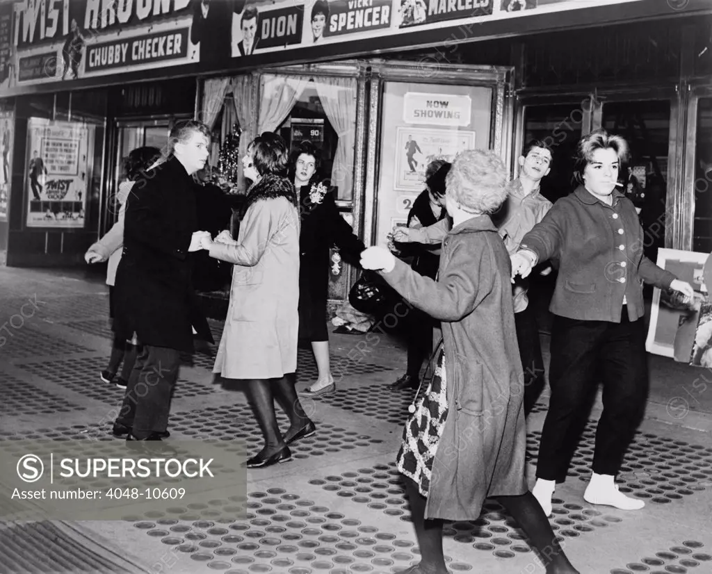Teens dancing the 'Twist' outside the Brooklyn Fox Theatre before the premiere of the movie 'Twist Around the Clock'. 1961.