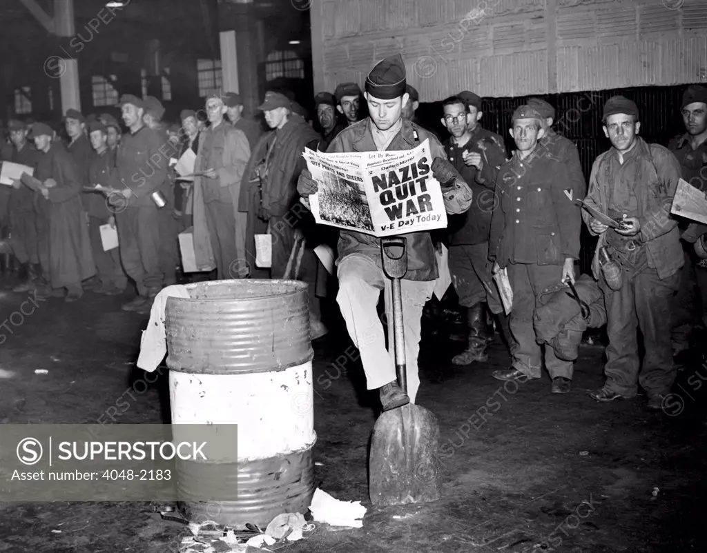 German prisoners of war in New York on the day Germany surrendered, ending the war in Europe. The newspaper headline reads: 'Nazis Quit War. V-E Day Today', May 8, 1945.