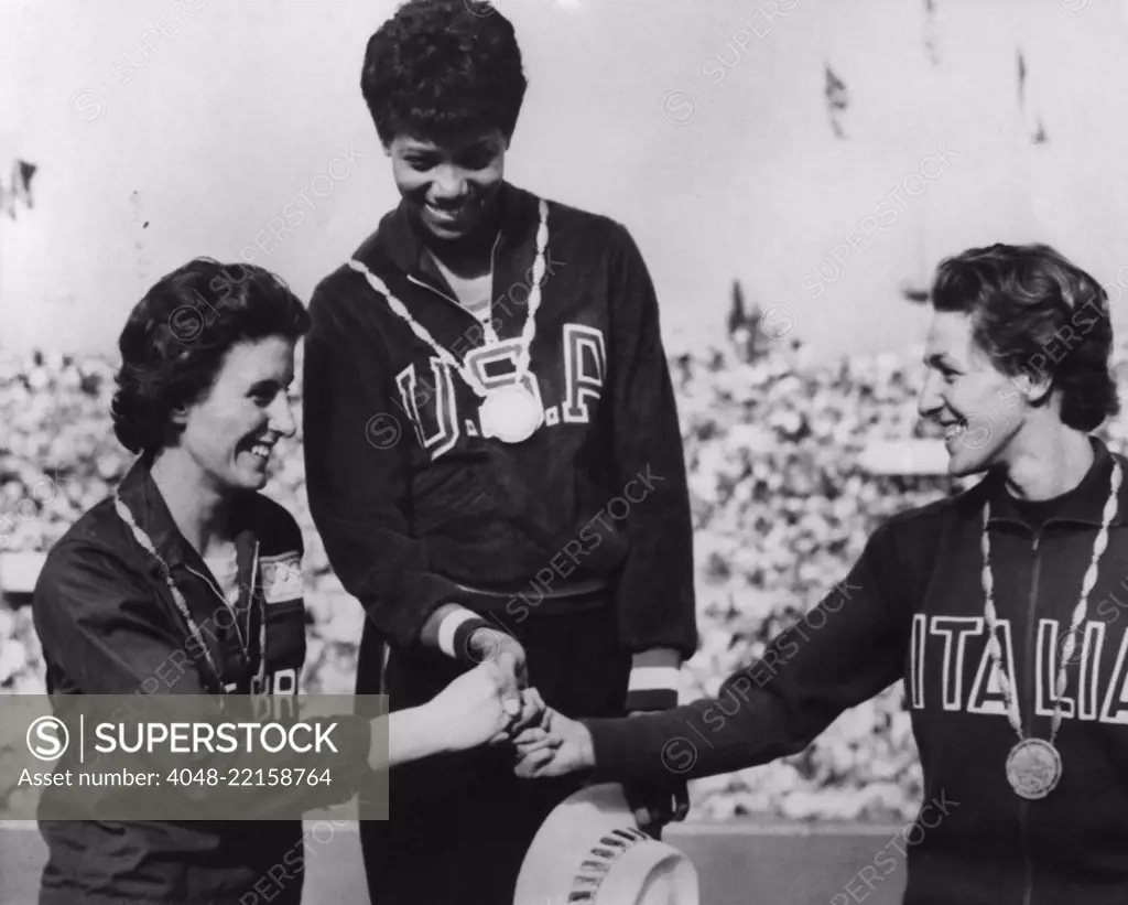 1960 Olympic winners of the women's 100 meter race on victory podium. First is Wilma Rudolph of USA. Dorothy Hyman of Great Britain is second, and Guiseppina Leone of Italy is third (BSLOC_2016_7_38)