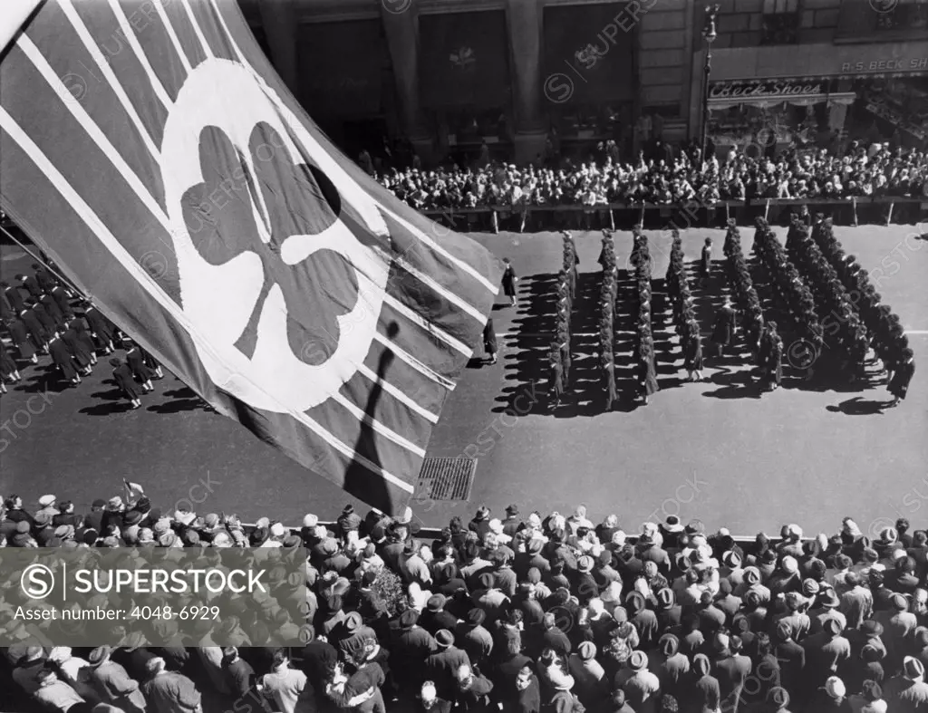 Flag with shamrock flies above Fifth Avenue as Saint Patrick's Day Parade passes below, New York City in 1961.