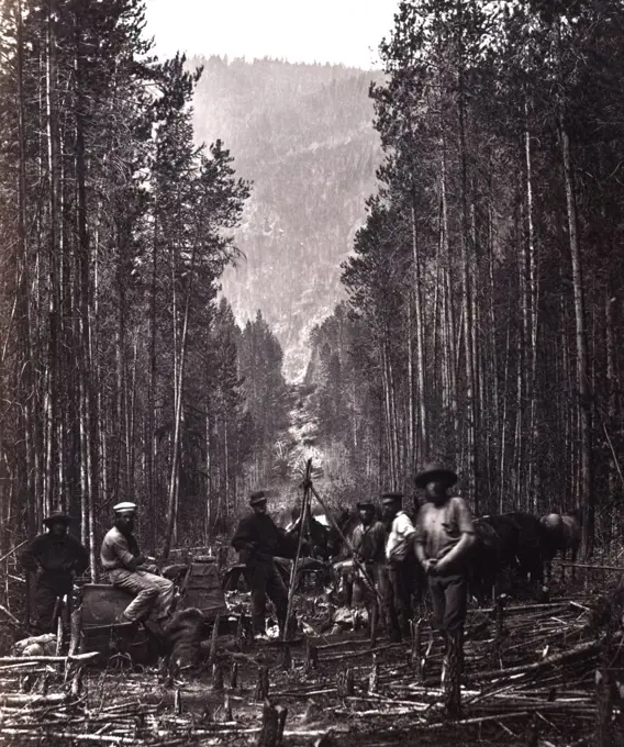 Cutting the boundary line. Men of the British North American Boundary Commission survey crew posed in clearing, with transit, marking the boundary line between Canada and the United States, along the right bank of the Moyie River, Idaho. ca. 1860