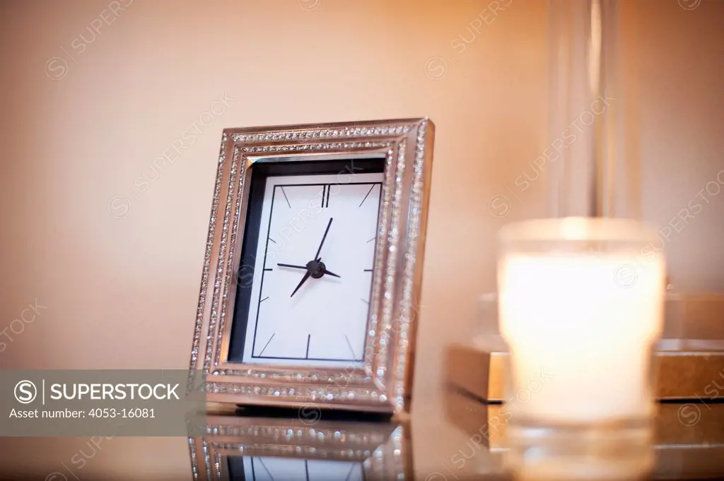 Close-up of candle and clock on end table against wall, Rancho Sante Fe, USA. California, USA. 01/23/2013