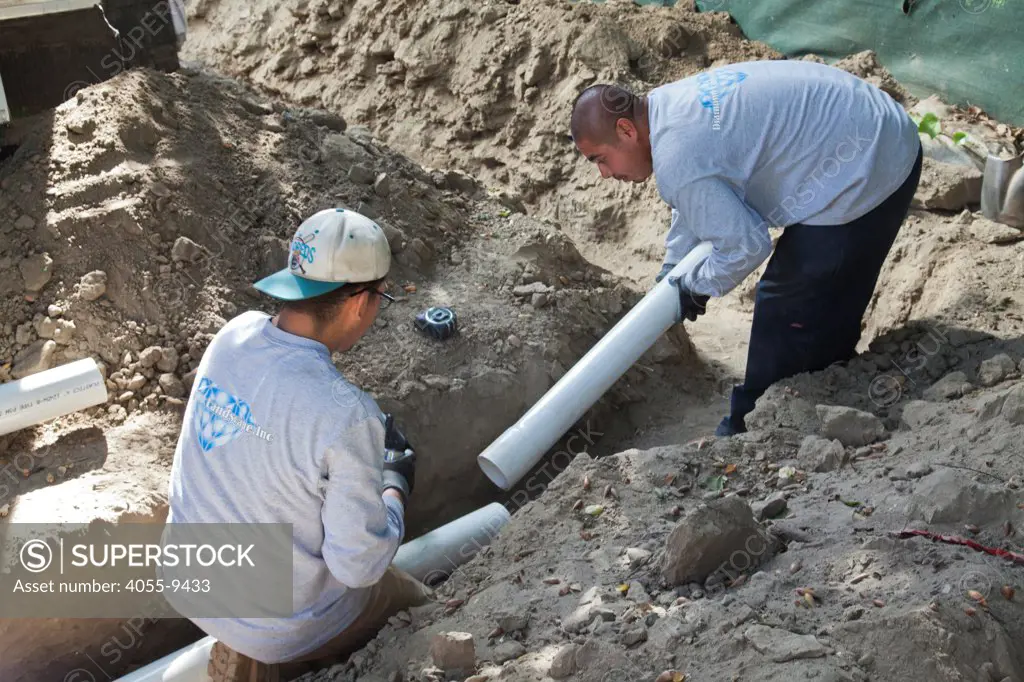 Poly Vinyl Chloride (PVC) Pipes being installed for rainwater harvesting system at new home construction. System is gravity based and relies on a 2% grade to carry captured water to cisterns or rain barrels in backyard. Los Angeles, California, USA