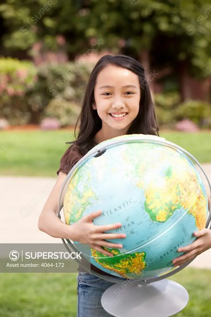 Middle school student holding a globe and smiling