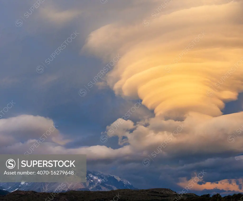 Sunset illuminating lenticular clouds, over Paine Grande, Torres del Paine National Park, Chile.