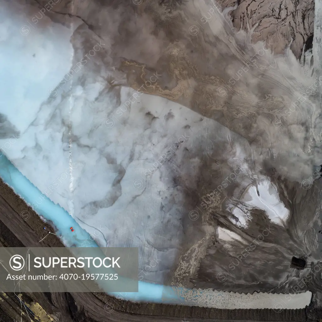 Aerial view of ash pond in East-Central Europe. After coal is burned in power plants, the waste ash is mixed with water and pumped through pipelines into sludgy lagoons commonly known as ash ponds. The ponds are used as landfill to prevent the release of ash into the atmosphere, but they also contaminate the environment with toxic pollutants harmful to human health. The vivid colour of the pond indicates the presence of chemicals used to neutralise the wastewater.