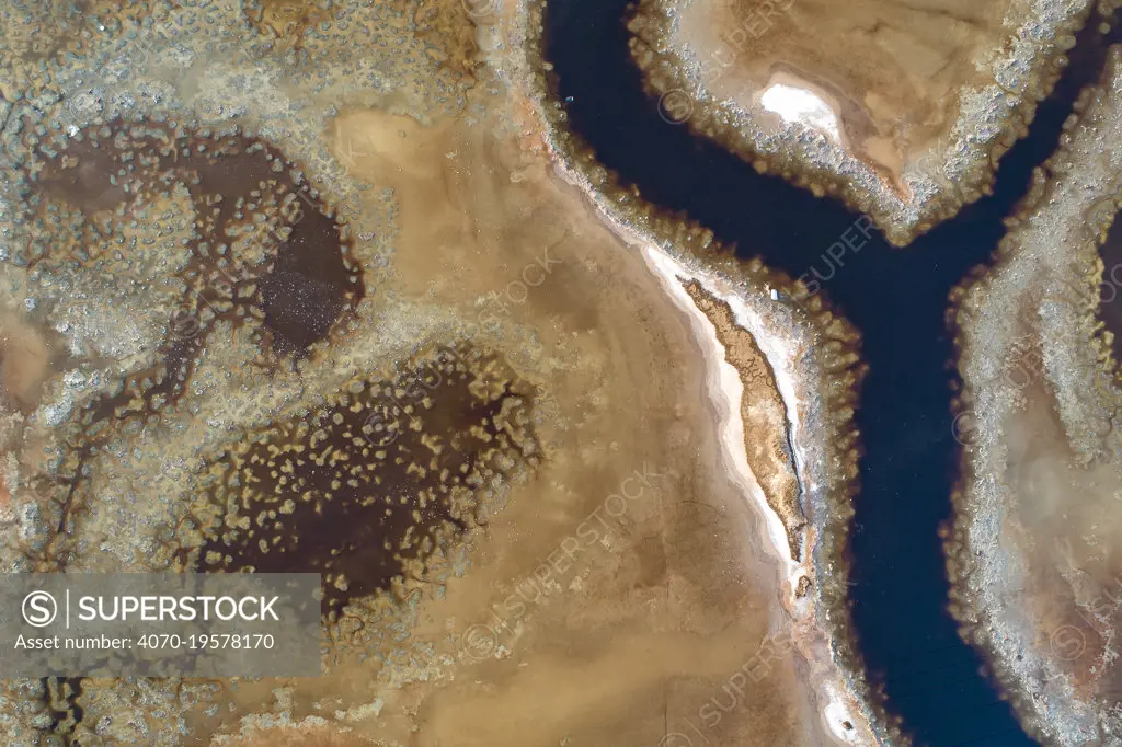 Coloured water leaking from photogypsum storage pond creates tidal channels in saltmarsh habitat. Huelva, Southern Spain. Phosphogypsum is a radioactive by-product in the manufacture of phosphoric acid, used for phosphate-based fertilizers.