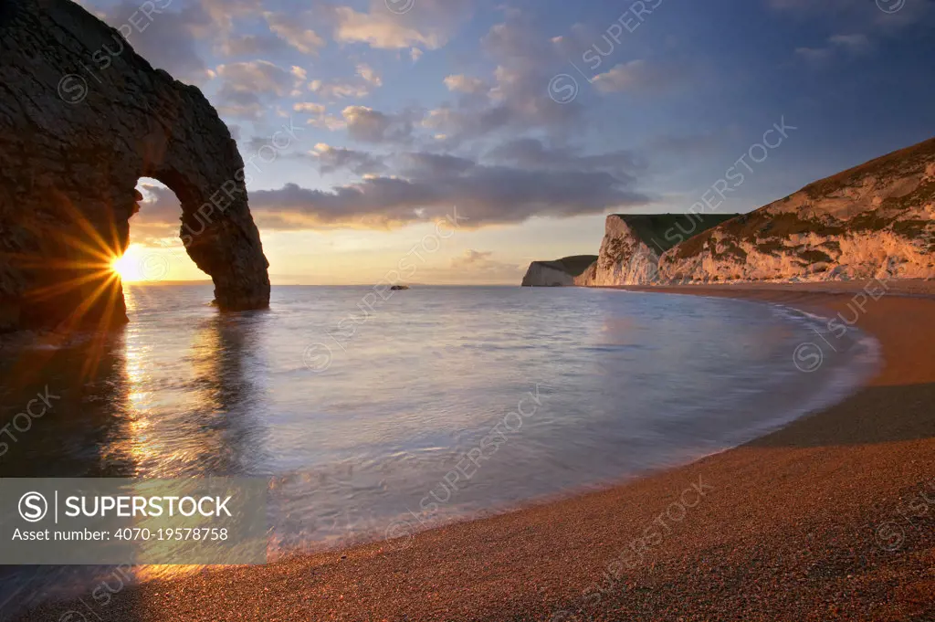 Setting sun shining through Durdle Door, Jurassic Coast, Dorset, England, December 2004