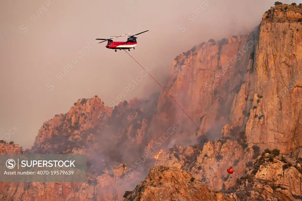 Lightning started fire on steep craggy terrain,  with  US Forest Service Fire suppression Wildland Firefighters using helicopters to 'bomb' the hot spots to control the spread. Pusch Ridge, Santa Catalina Mountains, Coronado National Forest, Arizona, USA. 6th June. June 2020.