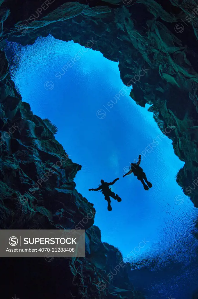 Pair of divers floating in Silfra Canyon, a deep fault filled with fresh water in the rift valley between the Eurasian and American tectonic plates) at Thingvellir National Park, Iceland. May 2011.  In this photo the American plate is on the left and the Eurasian plate on the right.