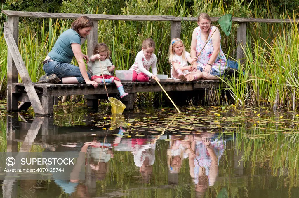 Children and mothers pond dipping and enjoying pond environment at Little Bradley Ponds, Bovey Tracy, Devon, UK. July 2011. Model released