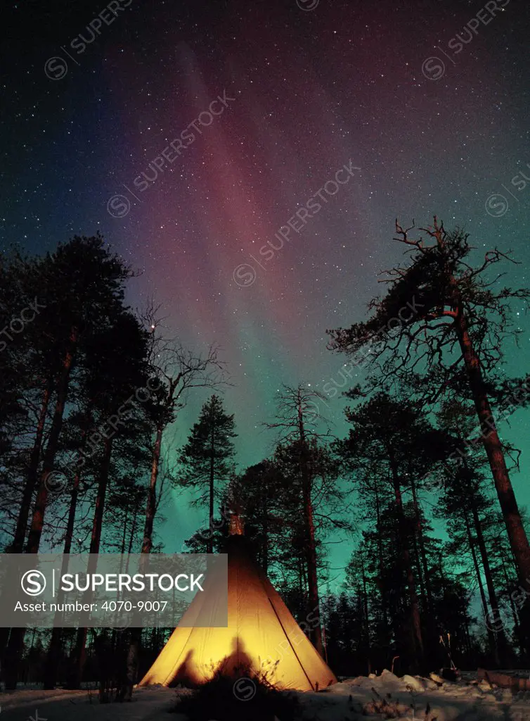 Aurora borealis colours in night sky above camp tent, Lapland, northern Finland, winter