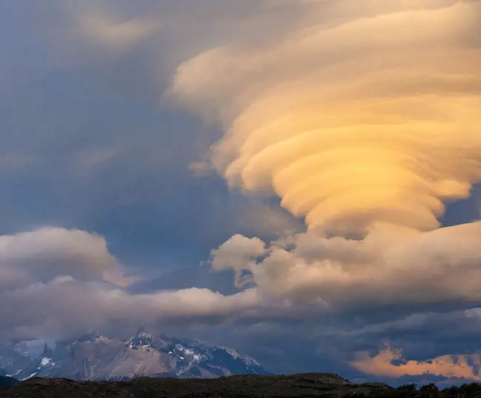 Sunset illuminating lenticular clouds, over Paine Grande, Torres del Paine National Park, Chile.
