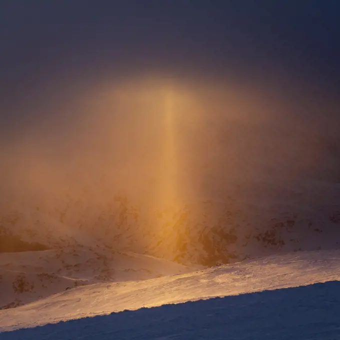 Sun pillar (optical phenomenon) that appears against the setting sun in light snow. Sognefjellet, Norway. April.