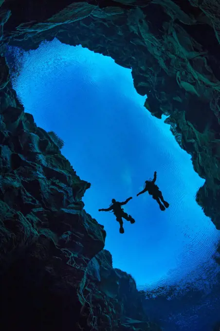 Pair of divers floating in Silfra Canyon, a deep fault filled with fresh water in the rift valley between the Eurasian and American tectonic plates) at Thingvellir National Park, Iceland. May 2011.  In this photo the American plate is on the left and the Eurasian plate on the right.