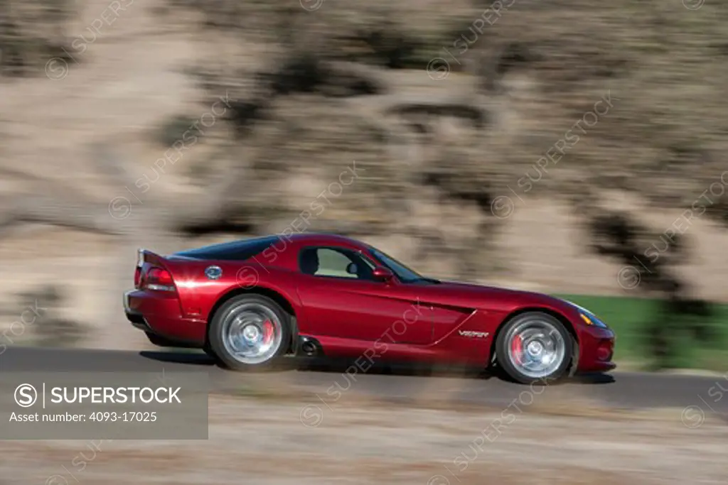 2009 Dodge Viper SRT-10 srt10 in Venom Red Metallic with white racing stripes driving fast through the hils of central California