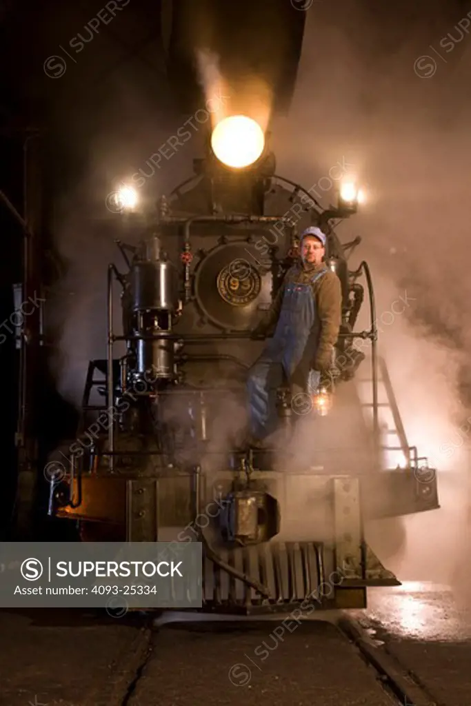 1909 Engine number 93 2-8-0 vintage steam locomotive inspected by a railroad museum worker using a vintage kerosene lamp