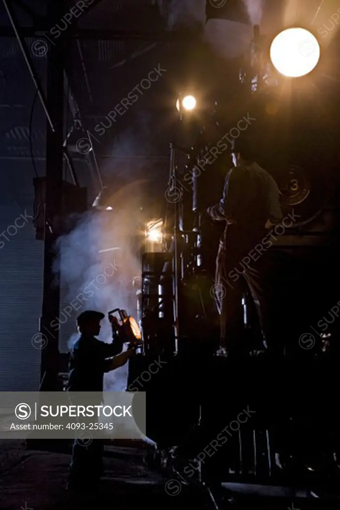 1909 Engine number 93 2-8-0 vintage steam locomotive inspected by a railroad museum worker using a vintage kerosene lamp