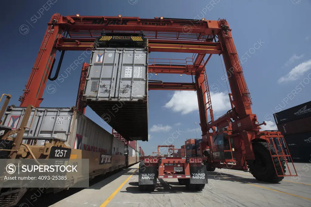 Crane loading a container onto a 2005 BNSF intermodal flat car, low angle view