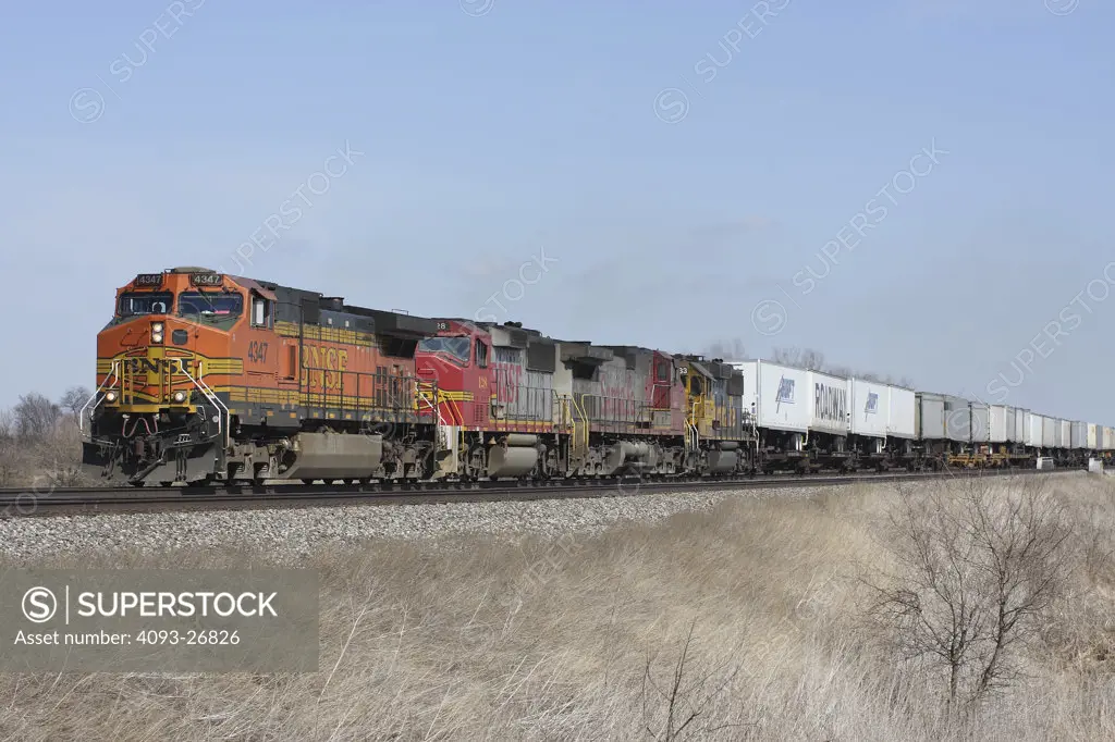 BNSF4347 Intermodal, General Electric Dash 9-44CW, 4 engine consist with various BNSF paint schemes and locomotive types, rural setting, westbound, MP135