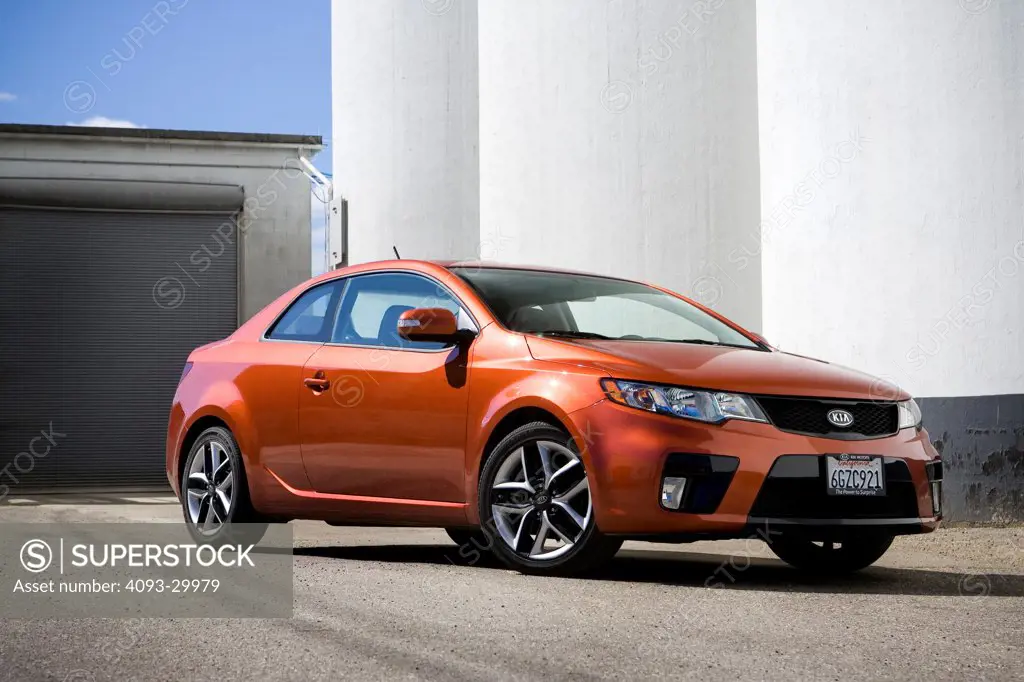 2010 Kia Forte Koup SX parked in front of an industrial location, front 3/4 static view