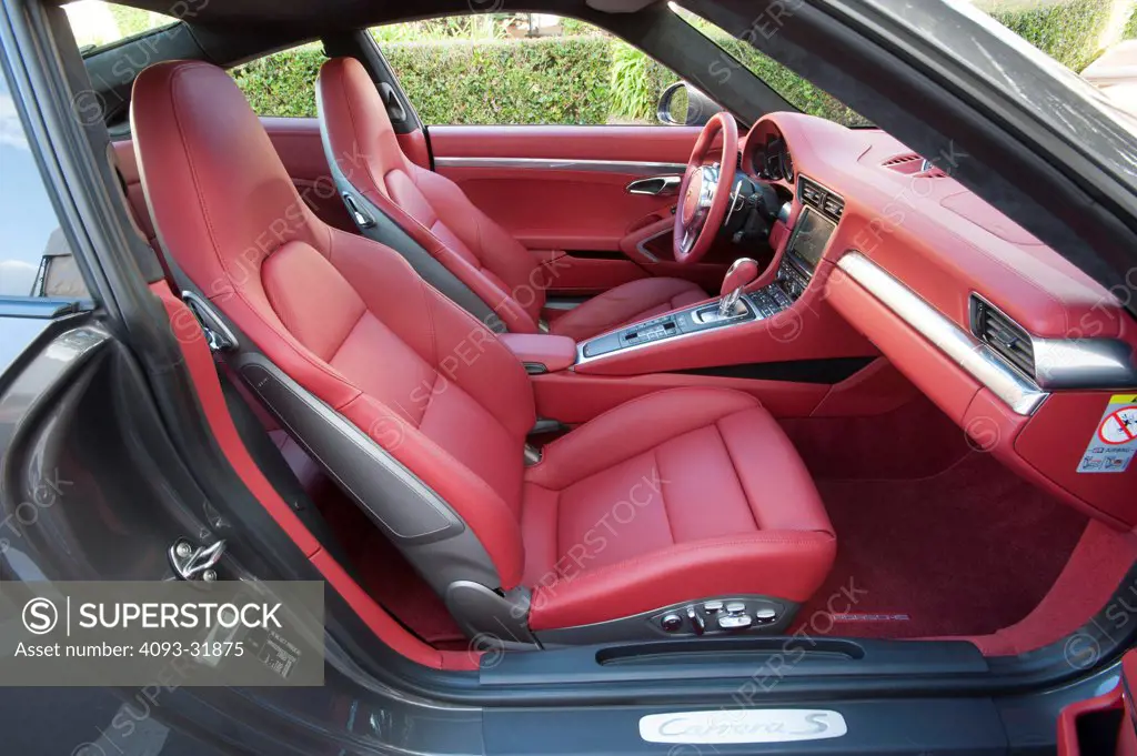 View of the red leather interior from the passenger's side of a 2012 Porsche 911 Carrera S. Porsche platform number 991 showing the steering wheel, dashboard and seats.
