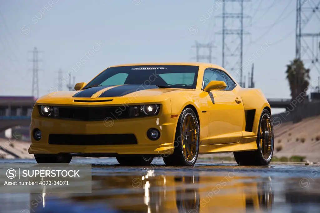 Static front 3/4 view of a yellow tuner 2011 Chevrolet Camaro Forgiato parked in the Los Angeles river.