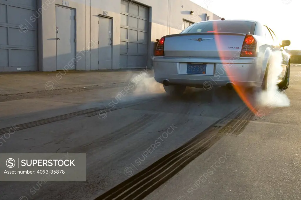 2006 Chrysler 300C SRT8 doing a burnout in an industrial location, rear view