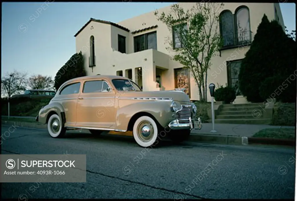 old 50's chevey falcon parked out front of a house.