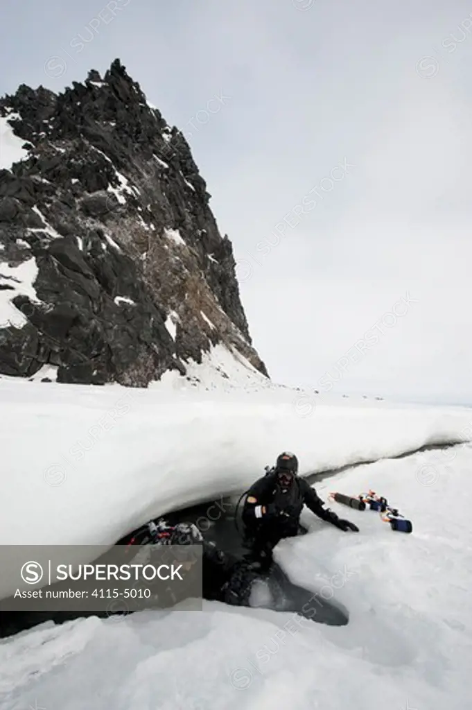 Doug Allan, BBC cameraman and another, entering ice-hole for underwater filming, McMurdo Sound, Ross Sea, Antarctica, November 2008