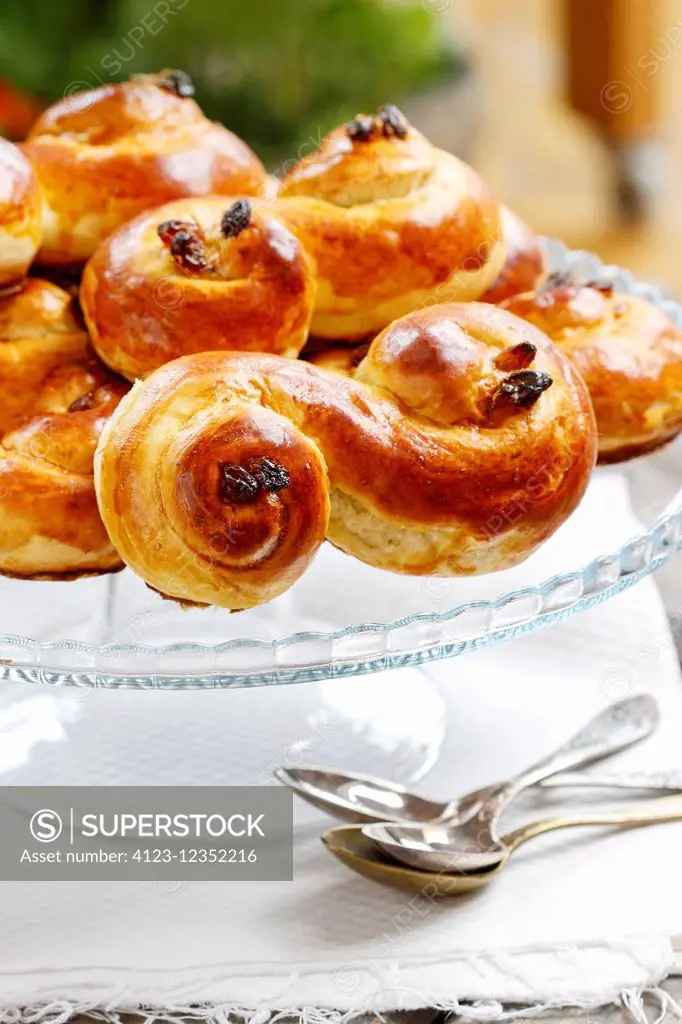 Swedish christmas. Traditional swedish buns on cake stand in christmas setting. A saffron bun, in Swedish lussebulle or lussekatt.