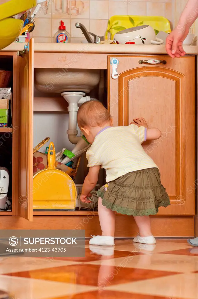 Baby At Home Rummaging In The Cupboard In The Kitchen Superstock